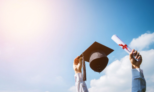 An image of arms holding a graduation cap and certificate against a bright sunny blue sky
