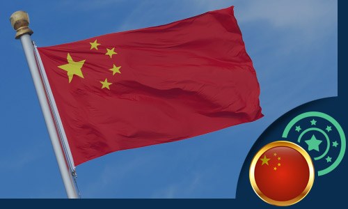 Chinese flag flying on a flagpole with the sky and clouds in the background